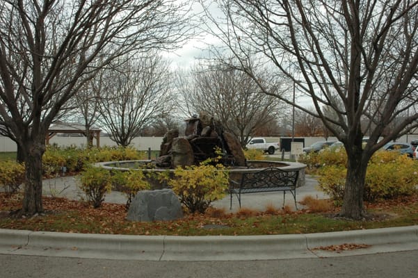 A decorative fountain surrounded by greenery in a senior living facility.