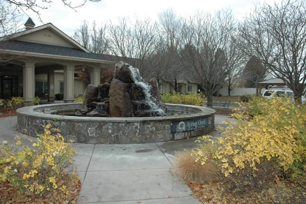 A decorative fountain with a rocky design surrounded by seasonal foliage.