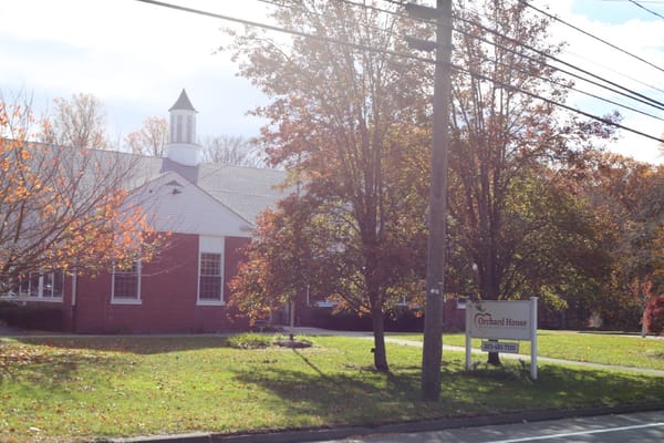 Exterior view of Orchard House with trees and sign