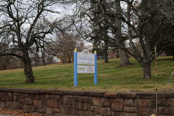 Sign for the Bradley Home surrounded by trees