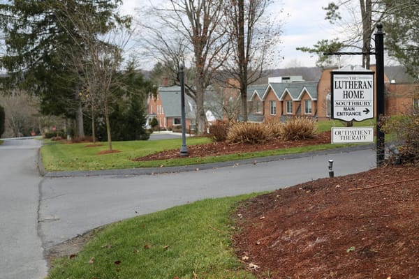 Sign for the main entrance of Lutheran Home of Southbury with buildings in the background