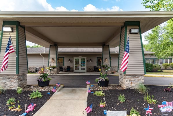 Exterior view of the facility entrance with flags and flowers