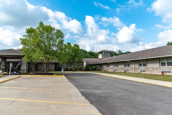 Exterior view of the assisted living facility with trees and parking