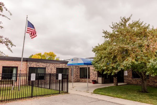 Front entrance of Pelican Valley Senior Living with American flag