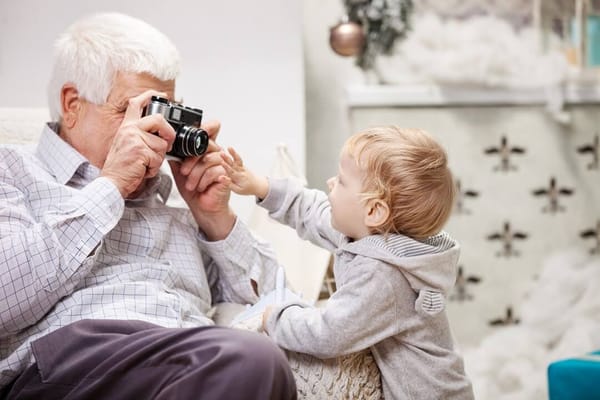 An elderly man playfully interacting with a toddler