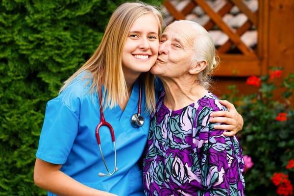 A caregiver and a resident share a joyful moment outdoors