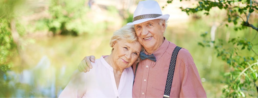Two smiling seniors posing together outdoors