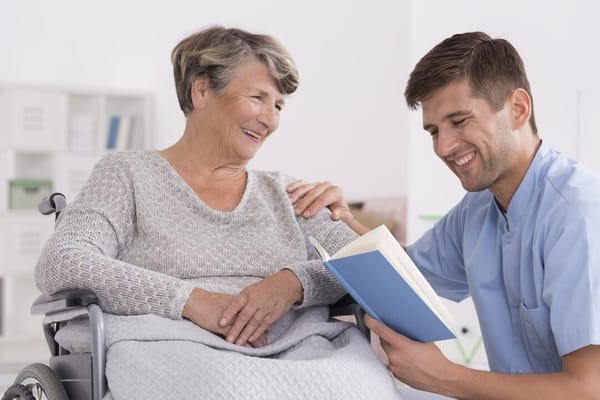 Caregiver reading to a resident in a bright room