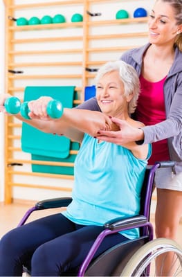Resident exercising with staff assistance in a therapy room