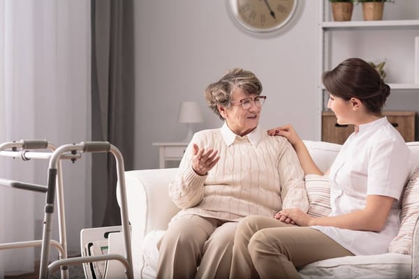A caregiver talking with an elderly resident in a bright living space