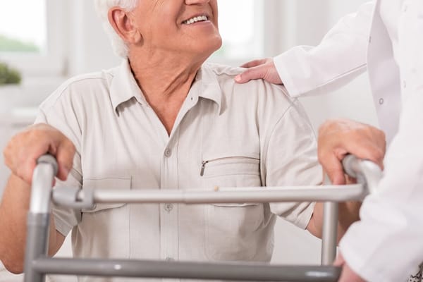 An elderly man receiving assistance from a caregiver