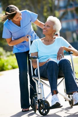 Caregiver assisting a resident in a wheelchair outdoors