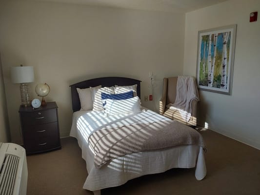 Brightly lit resident room with a bed and artwork