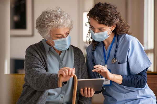 Nurse assisting senior resident with a tablet