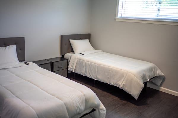 Two neatly made beds in a bright room