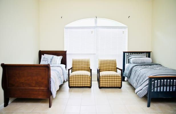 Room with two beds and two chairs by a window