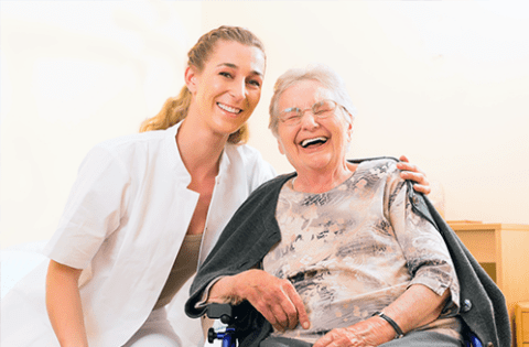 A caregiver and a resident smiling together in a facility setting