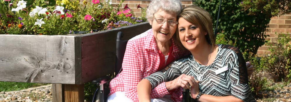 Resident and staff member smiling in a garden