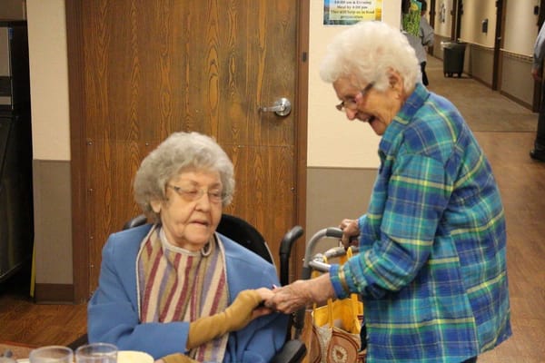 Two elderly women interacting in a cozy common area