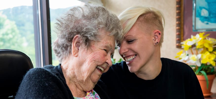 Resident laughing with staff member in a bright room