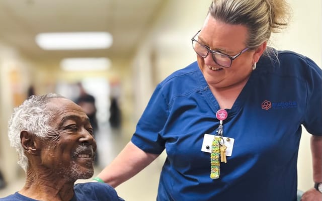 Staff member smiling with a resident in a hallway