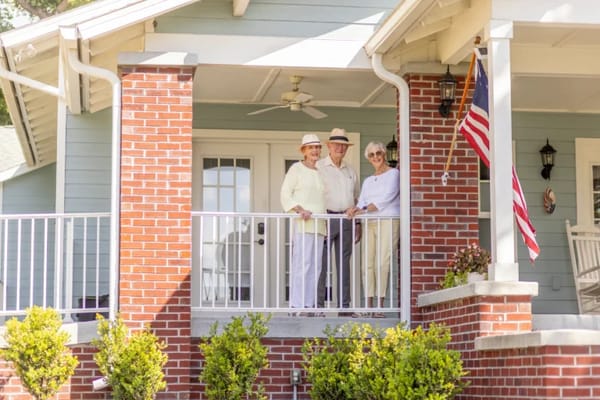 Residents enjoying the porch with greenery and flag