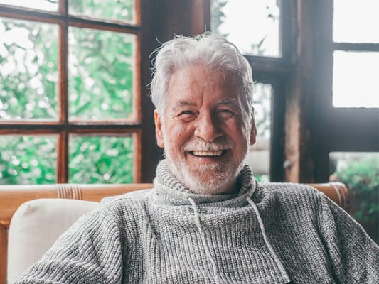 Elderly man smiling warmly in a cozy indoor setting