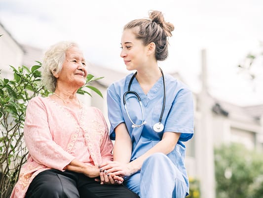 A caregiver and elderly resident sitting outdoors