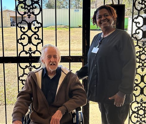 A staff member with a resident in a wheelchair outside