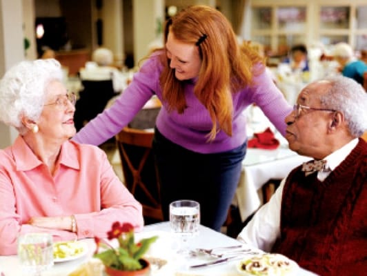 Residents enjoying a meal with staff in a dining area
