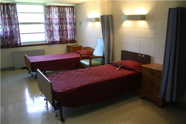 A shared resident room with two beds and furniture