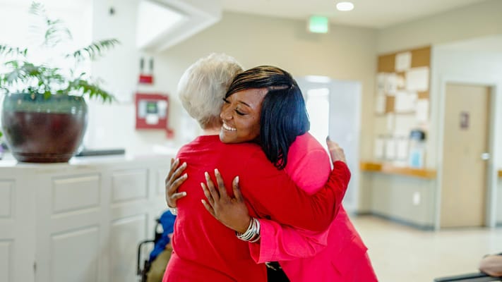 Two residents hugging in a welcoming lobby area