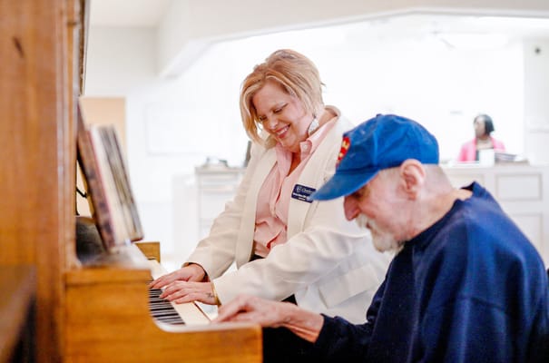 Staff member assisting resident at a piano