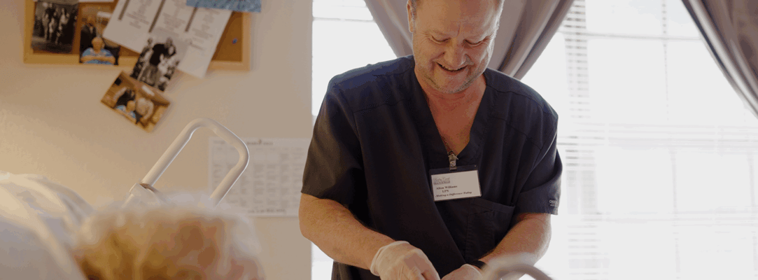 Staff assisting a resident in a facility room