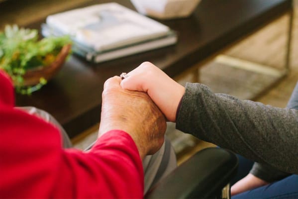 Close-up of a resident's hand held by a caregiver