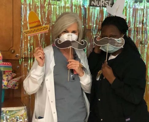 Two staff members with fun props in a common area