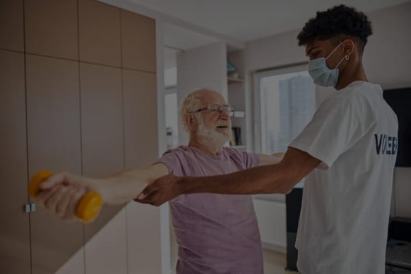 A caregiver assisting a resident with exercise in a bright room