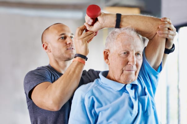 Personal trainer assisting an elder with exercise