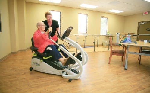 Resident exercising with staff in a therapy room