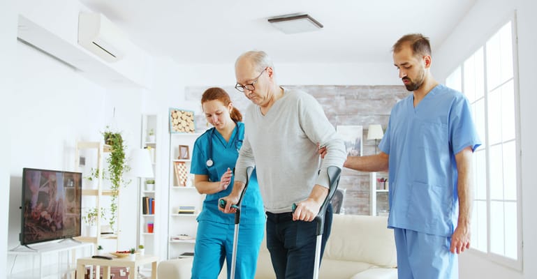 Healthcare staff assisting a senior in a living room