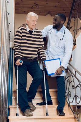 A caregiver assisting an elderly man on stairs