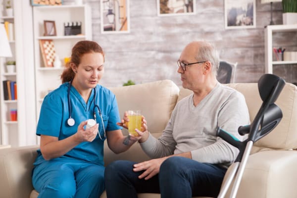 Caregiver assisting a senior man with medication