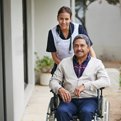 Nurse assisting a resident in a wheelchair outdoors