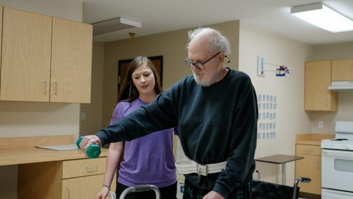 Care staff assisting a resident with weights