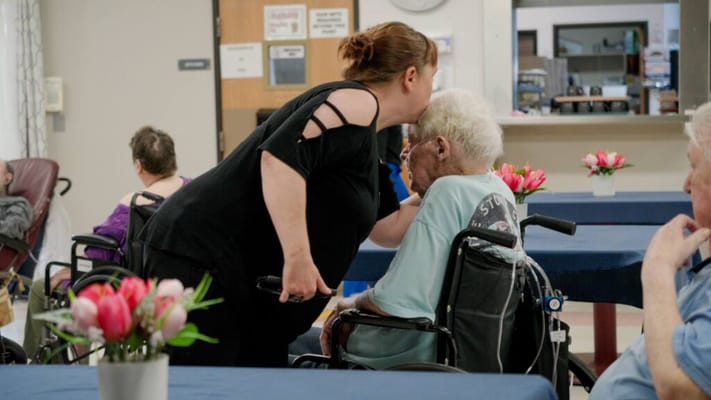 Caregiver assisting a resident in a communal room