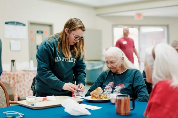 Staff serving a meal to a resident in a dining room