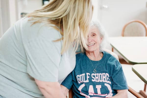 A staff member interacting with a smiling resident
