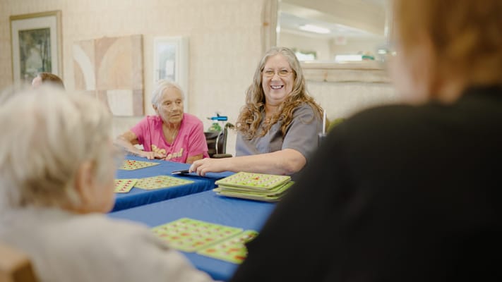 Residents engaging in a bingo activity with staff assistance
