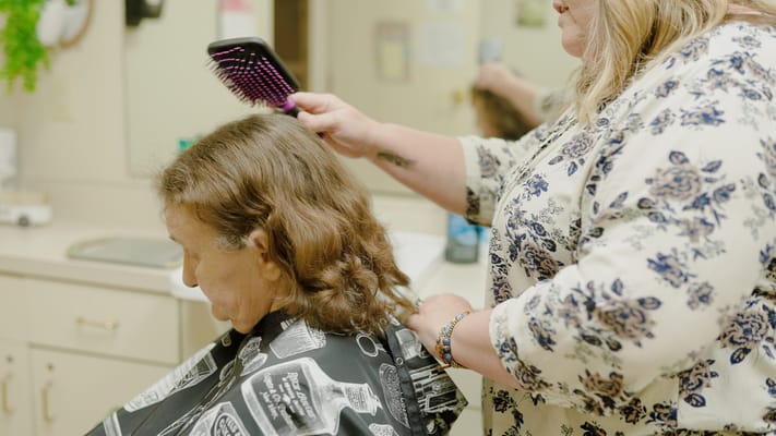 Stylist brushing a resident's hair in a salon area