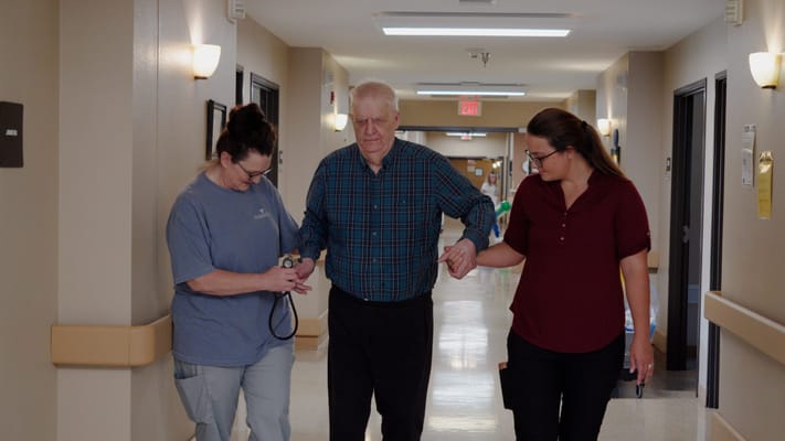 Staff assisting a resident in a brightly lit hallway